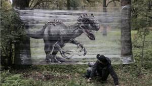 Taiteilija tekee graffiteja metsään levitettyihin kelmuihin. Tässä tulos.